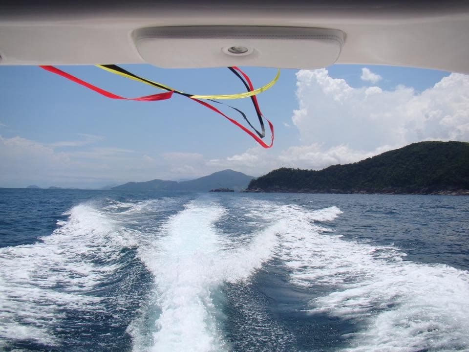 Vista de dentro de uma lancha em movimento, com ilhas e costão ao fundo